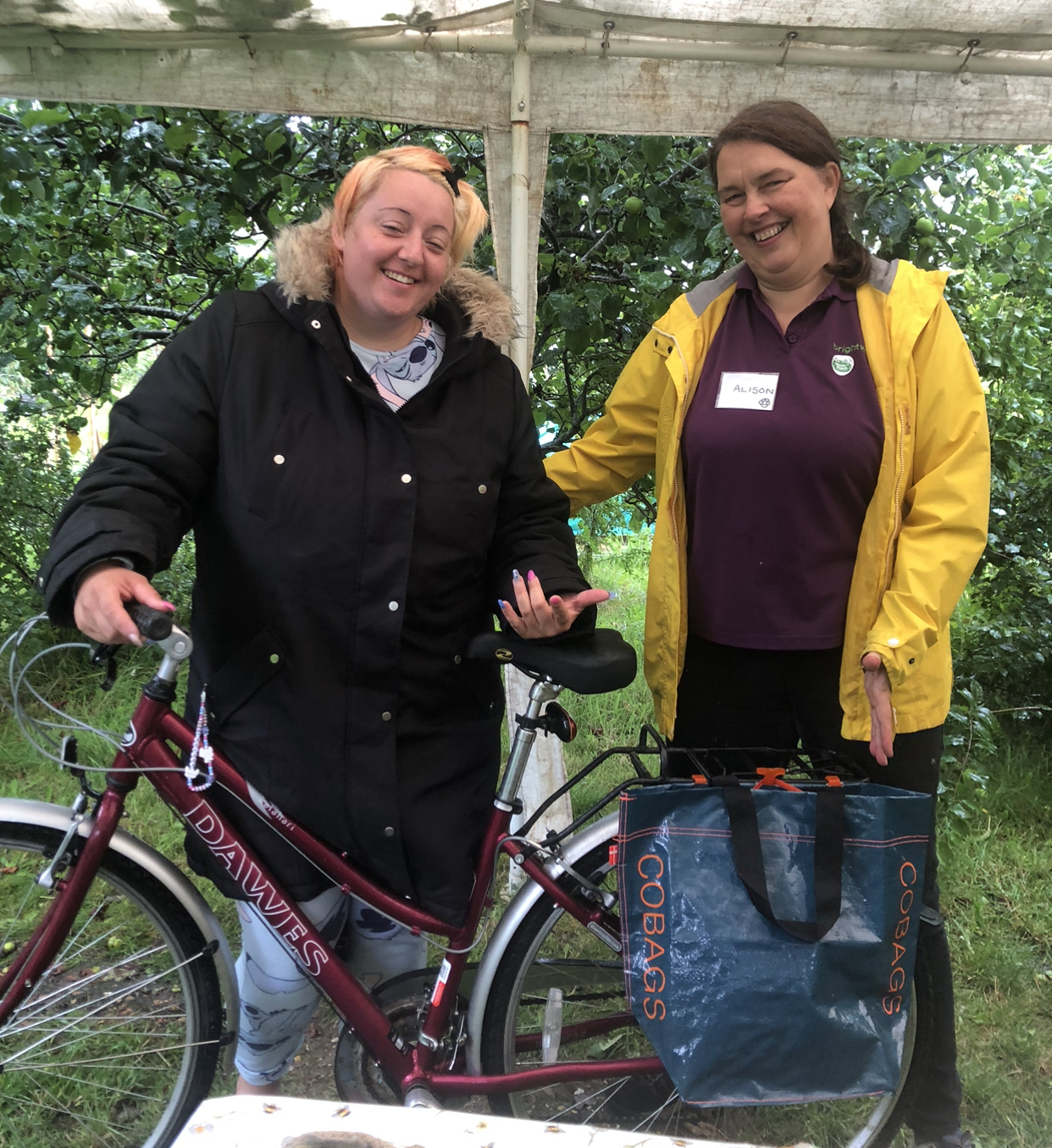 Two women smiling behind a bike