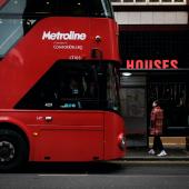 Double decker bus parked at a bus stop with a passenger ready to embark