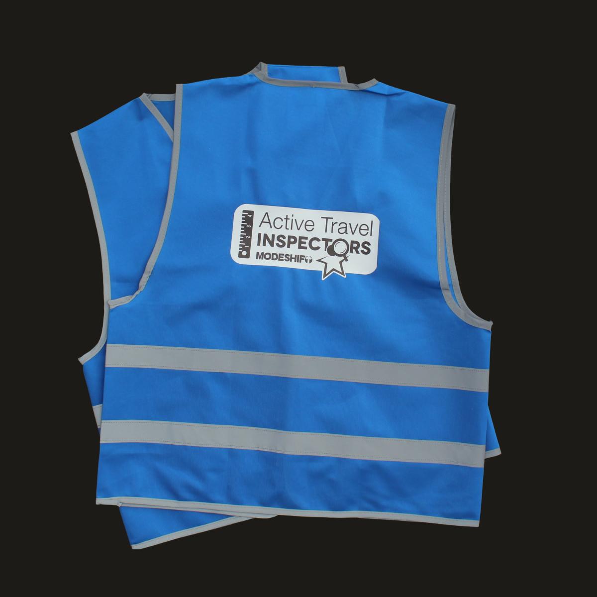 pair of blue high vis waistcoats with Active Travel Inspectors logo on back.