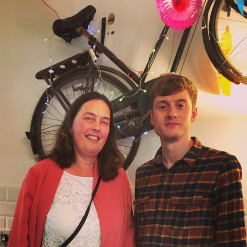 2 people standing with a wall mounted bike behind them