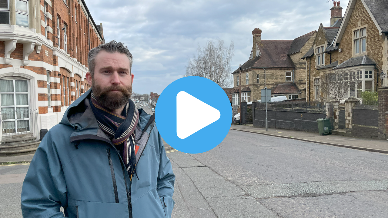 Simon Stokes walking w play button.