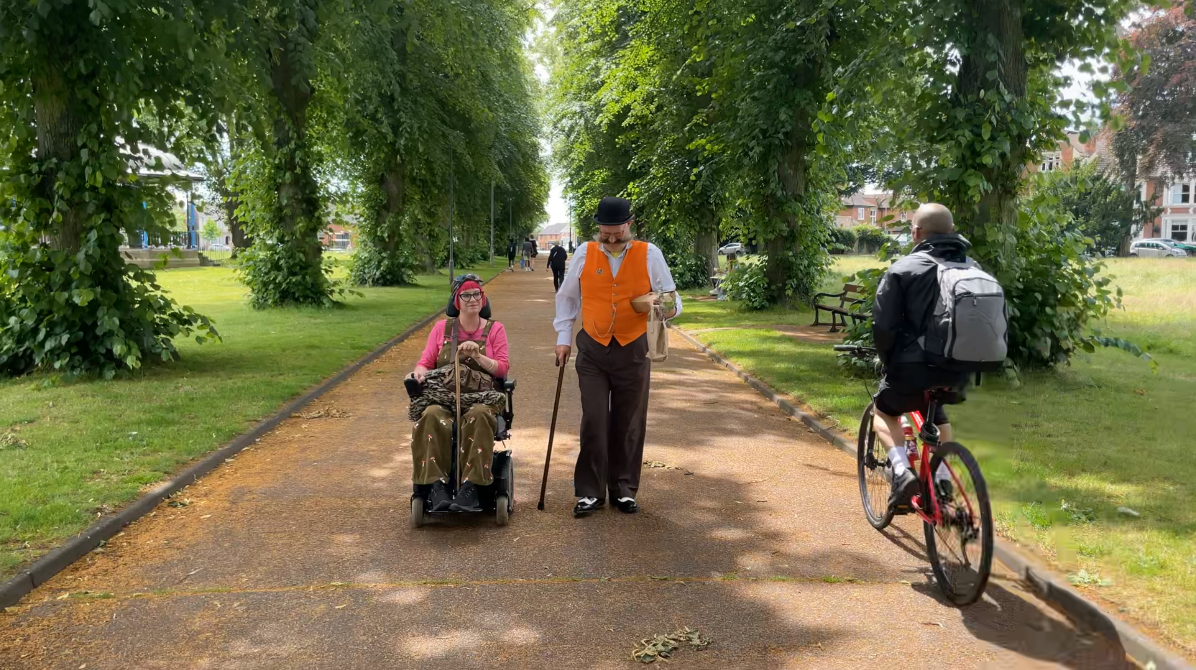 Power chair user in park with partner and cyclist