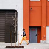 gentleman, mid stride walking past the fire door or an orange building.